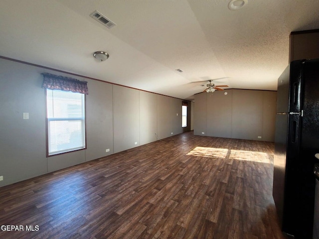 spare room with ceiling fan, a textured ceiling, vaulted ceiling, and dark hardwood / wood-style floors