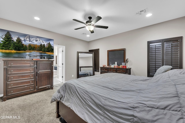 bedroom featuring ensuite bath, light colored carpet, and ceiling fan