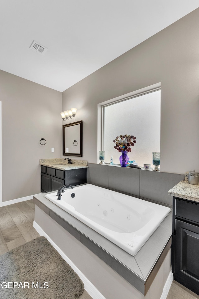 bathroom featuring vanity, wood-type flooring, and a bath