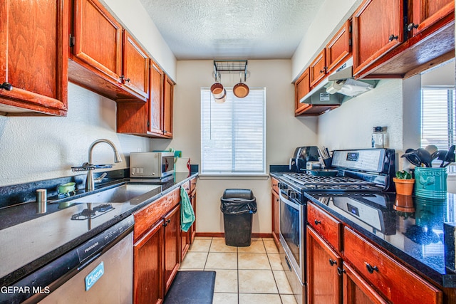 kitchen with appliances with stainless steel finishes, a textured ceiling, light tile patterned floors, and sink