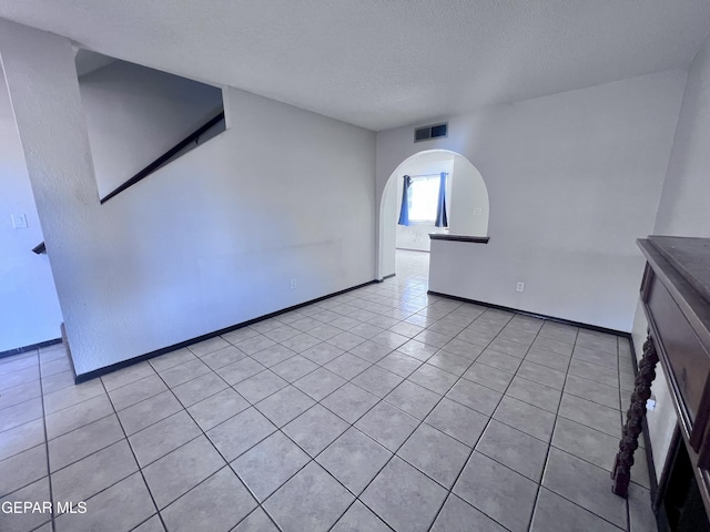 unfurnished living room with light tile patterned flooring and a textured ceiling