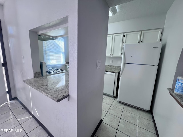 kitchen with white cabinets, a textured ceiling, white appliances, and light tile patterned flooring