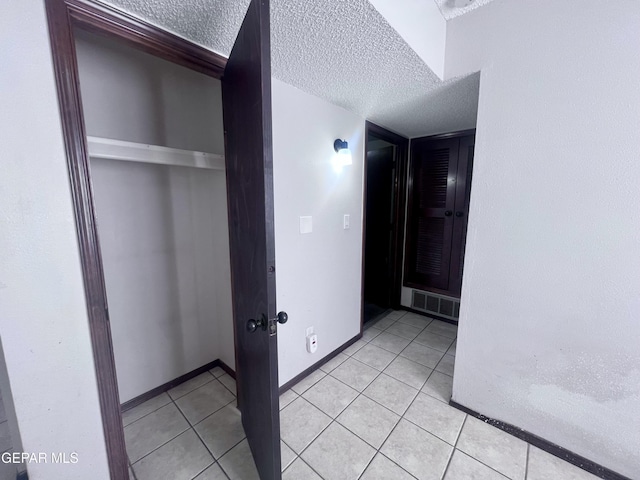 hall featuring light tile patterned floors and a textured ceiling