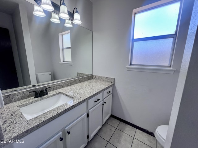 bathroom with toilet, vanity, and tile patterned floors