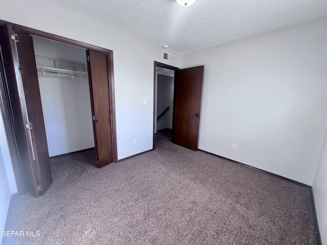 unfurnished bedroom featuring a textured ceiling, carpet floors, and a closet