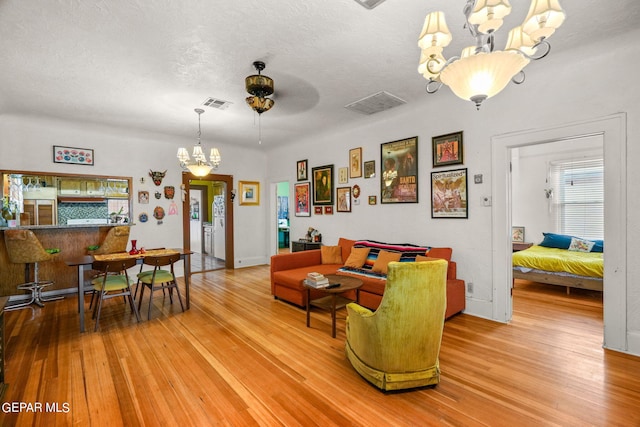 living room featuring a textured ceiling, light hardwood / wood-style flooring, and ceiling fan with notable chandelier