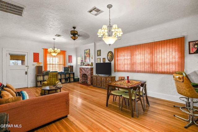 living room featuring a textured ceiling, hardwood / wood-style flooring, and ceiling fan with notable chandelier