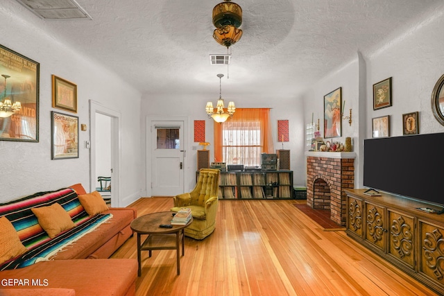 living room featuring a notable chandelier, hardwood / wood-style floors, a textured ceiling, and a fireplace