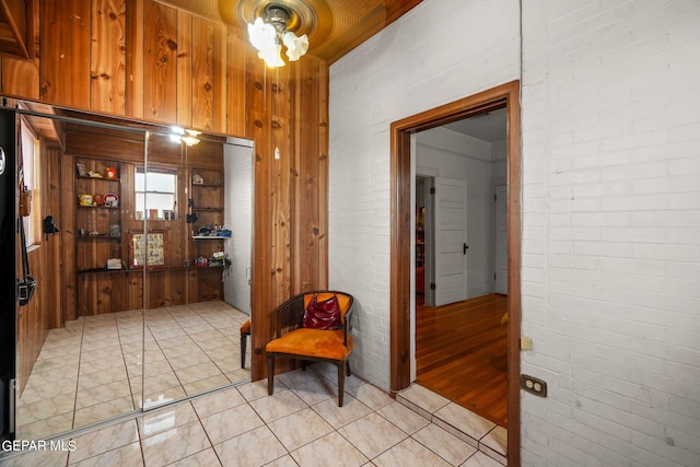 hall with brick wall, light tile patterned floors, and wooden walls