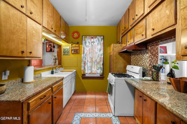 kitchen featuring sink, white range with gas cooktop, light stone counters, decorative backsplash, and light tile patterned floors