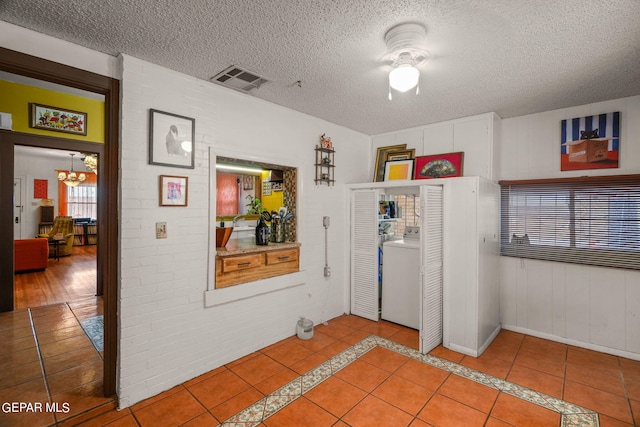 interior space featuring a chandelier, light tile patterned flooring, a textured ceiling, and washer / clothes dryer