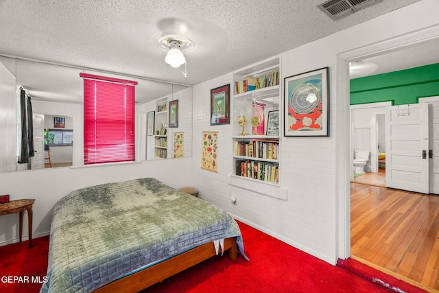 bedroom with connected bathroom, a textured ceiling, wood-type flooring, and ceiling fan