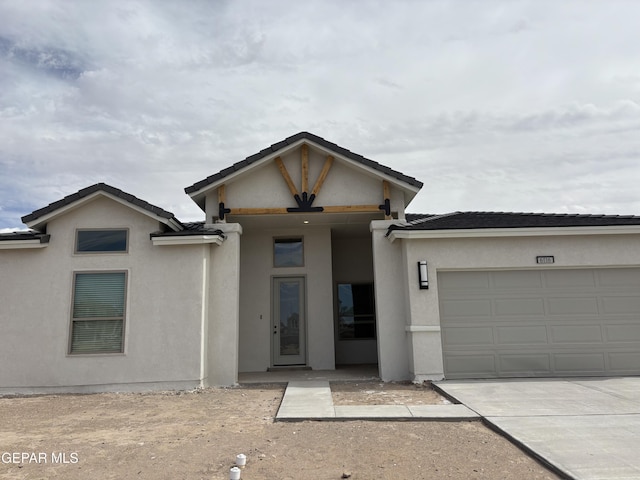 view of front of property featuring concrete driveway, an attached garage, and stucco siding