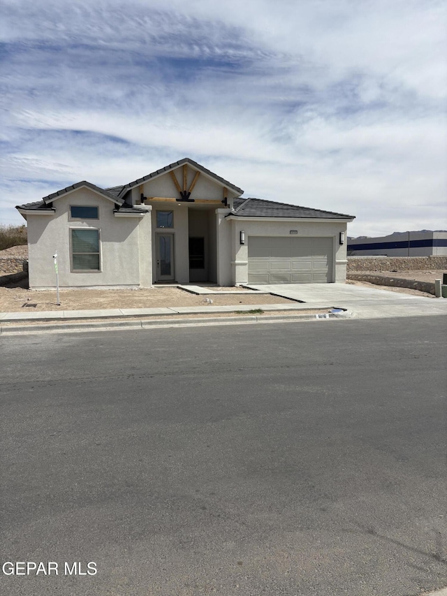 prairie-style home featuring stucco siding, driveway, and a garage