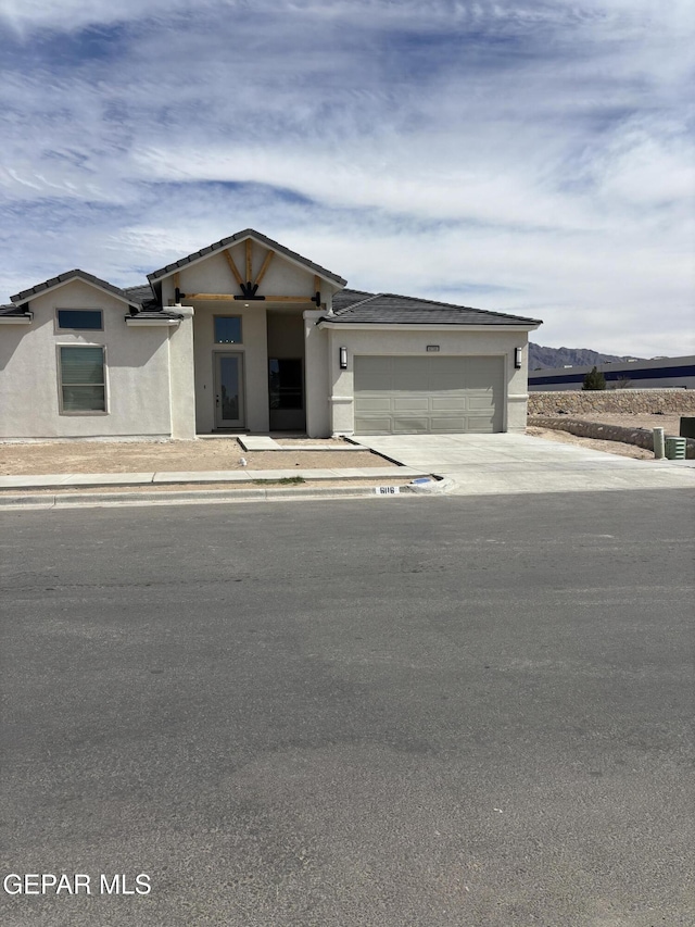 prairie-style home with concrete driveway, a garage, and stucco siding