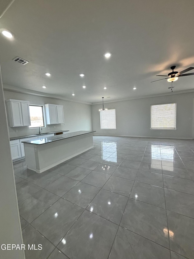 kitchen with recessed lighting, white cabinets, crown molding, open floor plan, and a center island