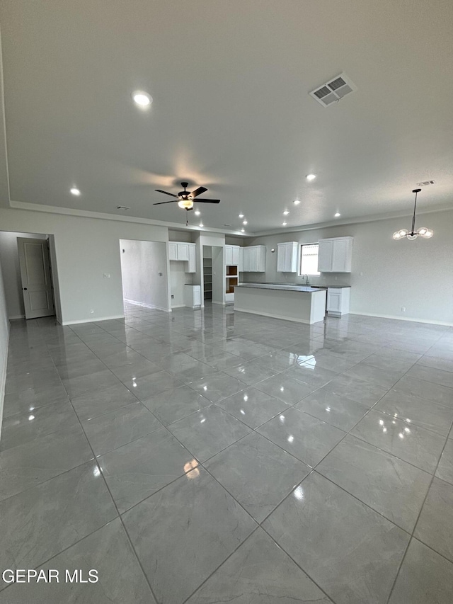 unfurnished living room with visible vents, ceiling fan with notable chandelier, crown molding, and baseboards