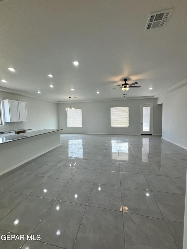 unfurnished living room featuring visible vents, baseboards, crown molding, and ceiling fan with notable chandelier