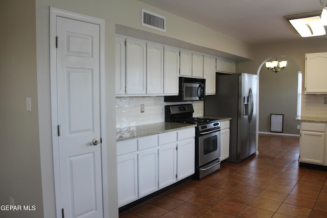 kitchen with light stone countertops, white cabinetry, stainless steel appliances, and tasteful backsplash