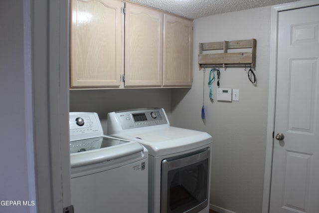 laundry area with cabinets, a textured ceiling, and washing machine and clothes dryer