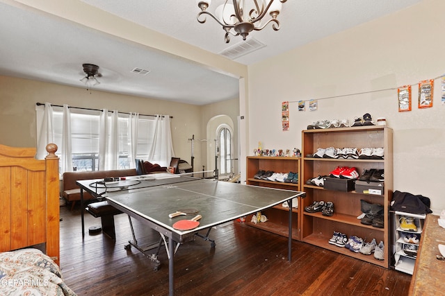 game room featuring dark wood-type flooring and ceiling fan with notable chandelier