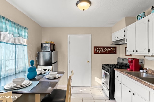 kitchen with sink, gas stove, stainless steel fridge, white cabinetry, and light tile patterned floors