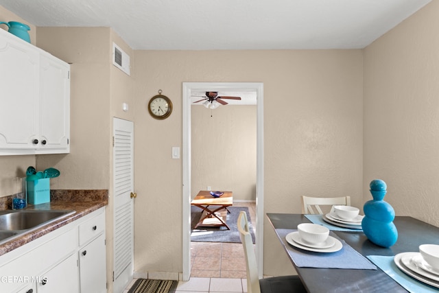 kitchen featuring white cabinets, sink, and light tile patterned floors