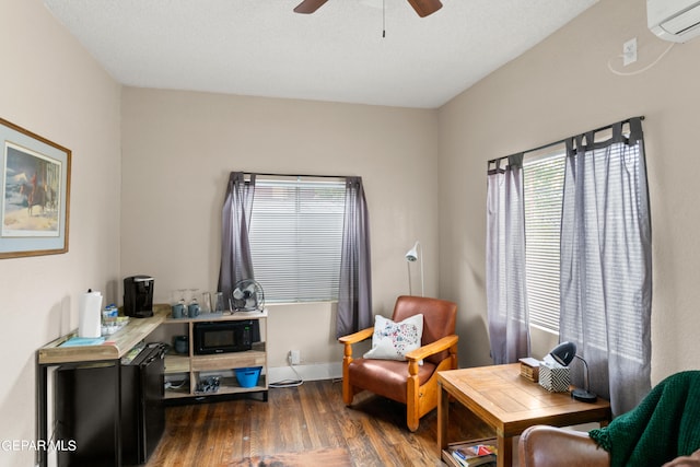 sitting room featuring dark wood-type flooring, ceiling fan, and a wall mounted air conditioner