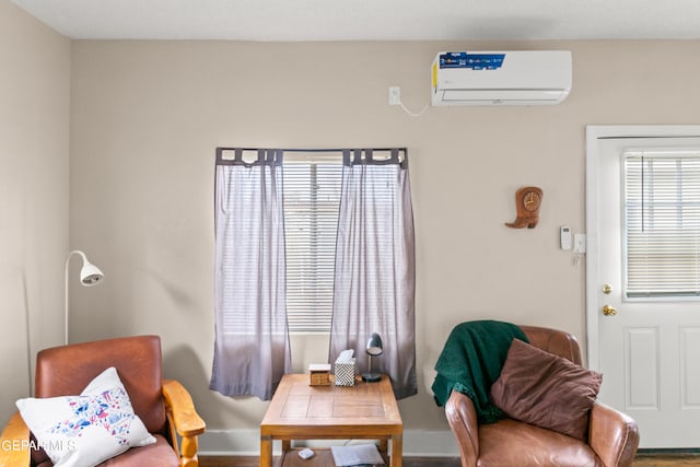 sitting room with a wall mounted AC and wood-type flooring