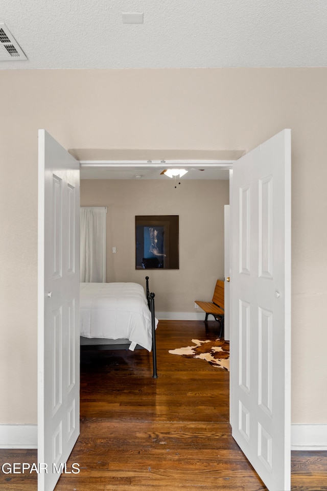 bedroom with ceiling fan, a textured ceiling, and dark hardwood / wood-style flooring