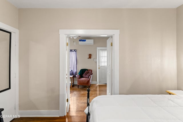 bedroom with a closet, a wall mounted AC, and wood-type flooring