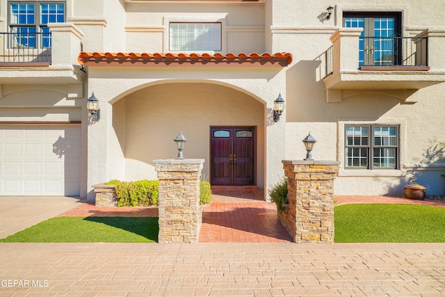 view of exterior entry with a balcony and a garage