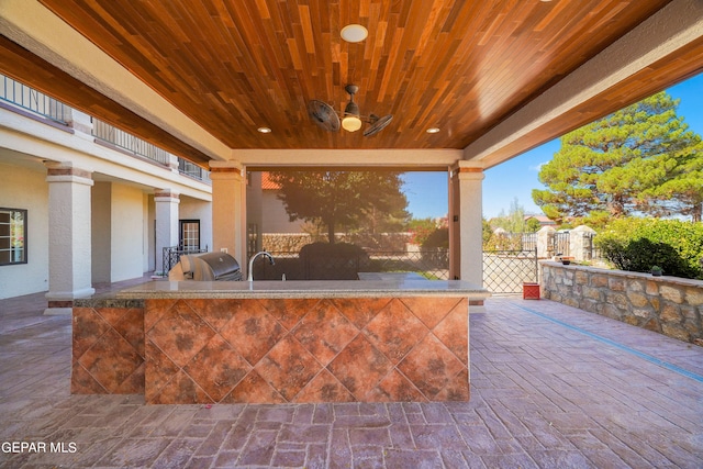 view of patio with sink, grilling area, a balcony, ceiling fan, and exterior kitchen