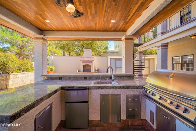 view of patio featuring a balcony, a grill, sink, and exterior kitchen