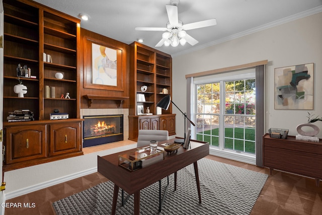 office space with a tiled fireplace, ceiling fan, and crown molding