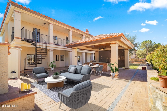 rear view of house with a balcony, ceiling fan, a patio, and an outdoor hangout area