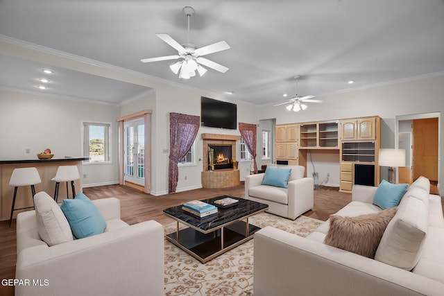 living room featuring light wood-type flooring, ceiling fan, and crown molding