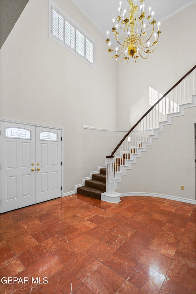 foyer entrance featuring a high ceiling, a chandelier, and ornamental molding