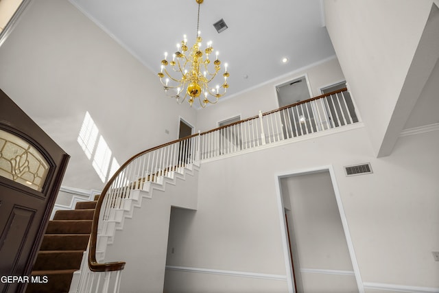 stairs featuring a towering ceiling, a chandelier, and crown molding