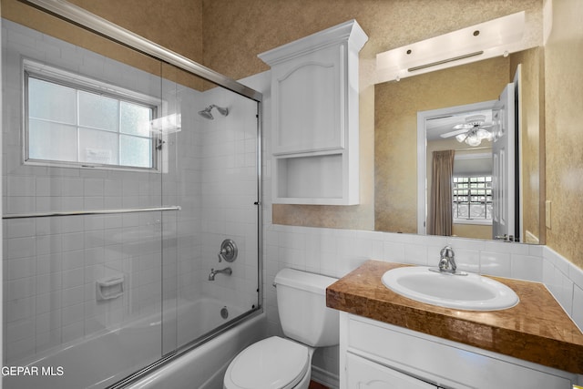 full bathroom featuring toilet, vanity, bath / shower combo with glass door, and ceiling fan