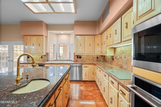 kitchen with dark stone counters, decorative backsplash, sink, and stainless steel appliances