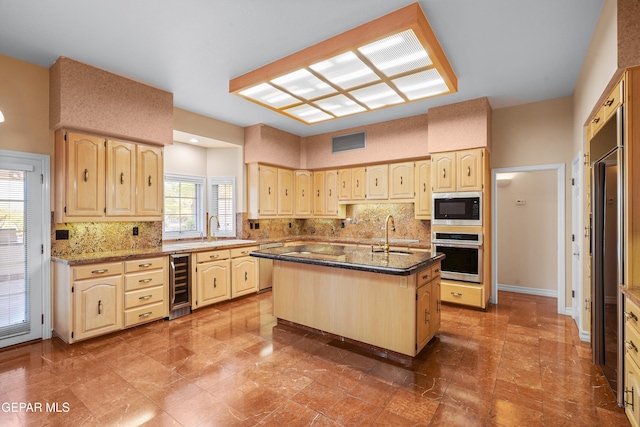 kitchen featuring wine cooler, appliances with stainless steel finishes, dark stone countertops, and a center island with sink