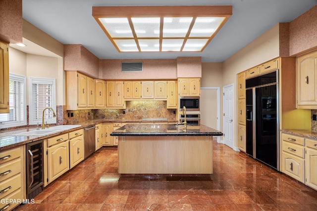 kitchen with built in appliances, wine cooler, sink, stone counters, and a kitchen island with sink