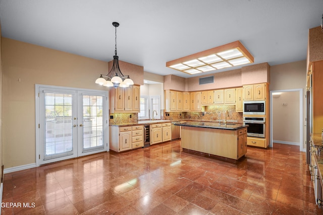 kitchen with a center island with sink, sink, appliances with stainless steel finishes, hanging light fixtures, and french doors