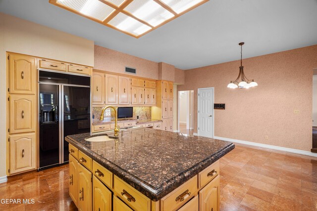 kitchen with sink, a chandelier, an island with sink, black built in fridge, and pendant lighting