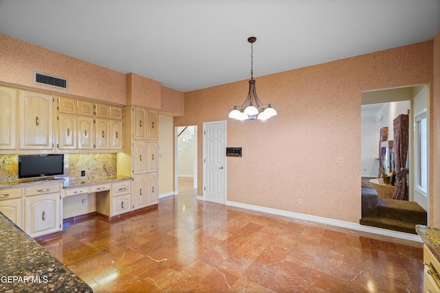 kitchen featuring a chandelier, hanging light fixtures, built in desk, and stone countertops