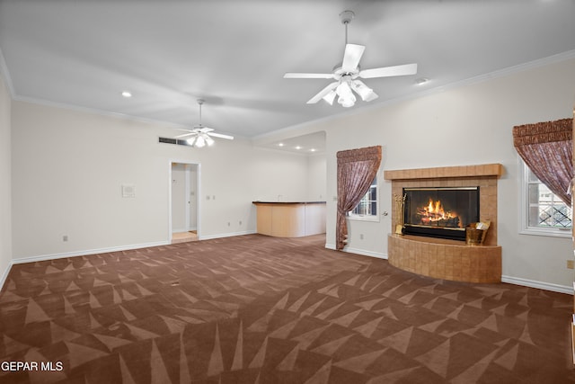 unfurnished living room with a tiled fireplace, ceiling fan, dark carpet, and crown molding