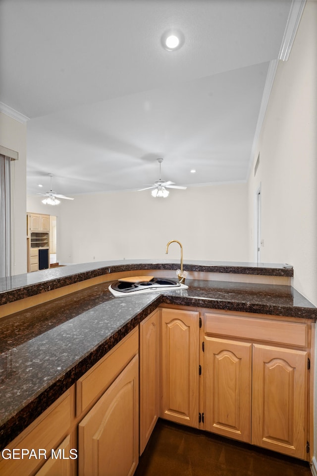 kitchen with dark stone countertops, light brown cabinetry, sink, and crown molding