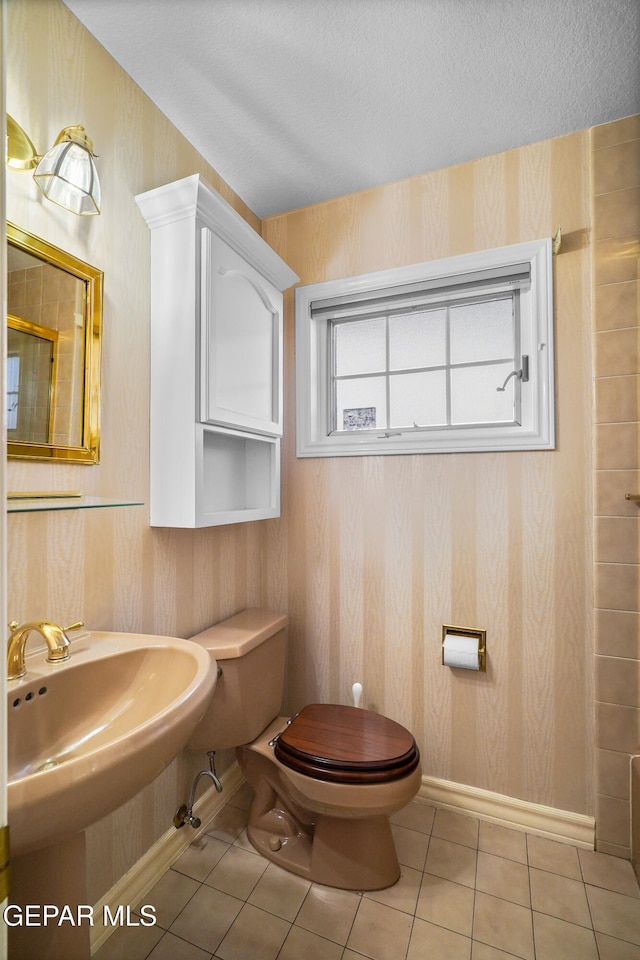 bathroom featuring tile patterned flooring, toilet, a textured ceiling, and sink