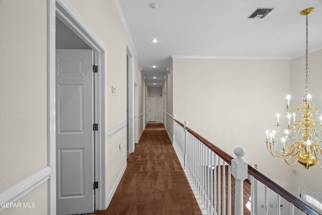 hallway with ornamental molding, dark colored carpet, and a chandelier